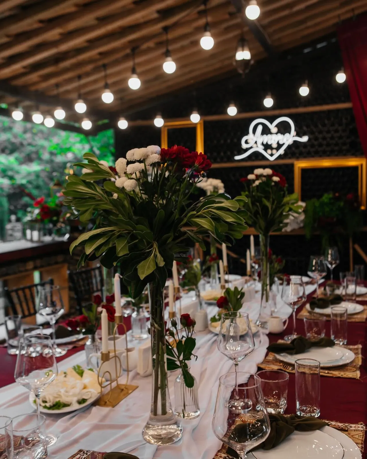 Evening reception with string lights and a wine-red table setting