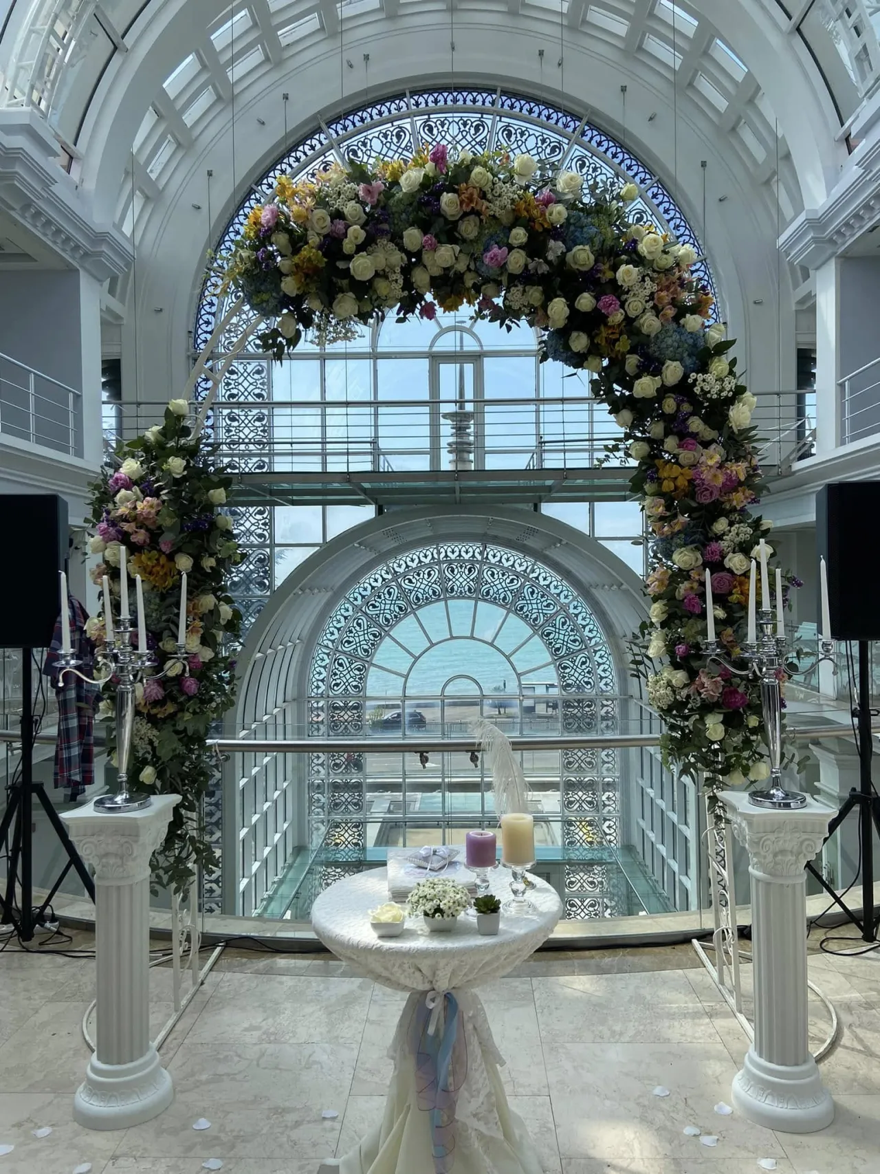 Flower arch in a white atrium with arched windows facing the sea