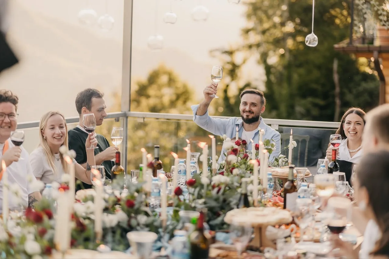Guests raising their glasses at a long table on a mountain terrace