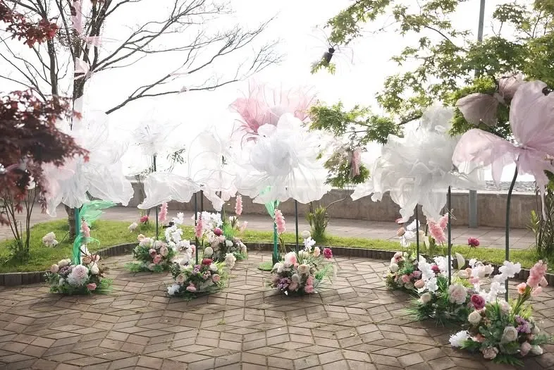 Large organza flower installations on a paved circle among the trees of a park